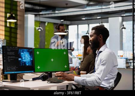 Technician writing code snippets on green screen computer in modern office, adjusting program configurations. IT worker running diagnostic tools on chroma key PC, monitoring API cloud services Stock Photo