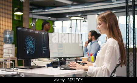 Female technician using AI LLM chatbot to automate tasks in office. IT specialist uses artificial intelligence large language model assistant, optimizing company systems performance, camera A Stock Photo
