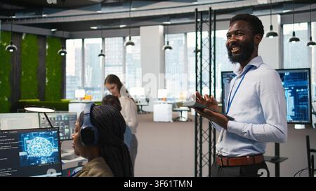 Happy programmer designing and developing software applications, optimizing code for performance and scalability. Joyous IT expert in office using tablet to resolving bottlenecks, camera A Stock Photo