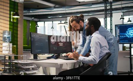 Programmer in office requesting help from coworkers to fix critical error warning. IT employee and colleagues brainstorming how to fix computer bug affecting systems, camera A Stock Photo