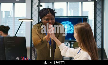 Happy manager praising intern progress with encouraging words, doing congratulating high five. Smiling team leader providing positive feedback for young female engineer at work, camera A Stock Photo