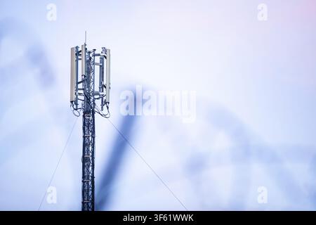 A horizontal photograph capturing a modern telecommunication cell tower with 5G and 4G antennas in sharp focus against a soft twilight sky, featuring Stock Photo