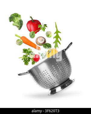 Fresh vegetables and colander in air on white background Stock Photo