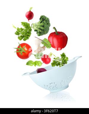 Fresh vegetables and colander in air on white background Stock Photo