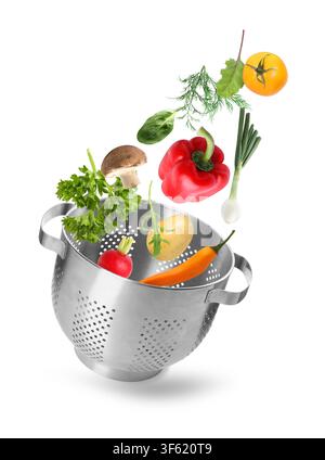 Fresh vegetables and colander in air on white background Stock Photo