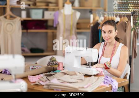 Woman seamstress operating by sewing machine Stock Photo