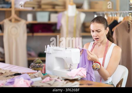 Upset female dressmaker looking at fabric in workshop Stock Photo