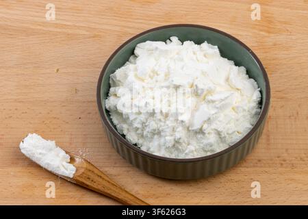 White Cornstarch Powder in Ceramic Bowl with Wooden Spoon Stock Photo