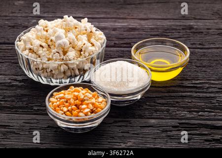 Composition of ingredients for making homemade popcorn, with corn kernels, sugar, oil, and ready-to-eat popcorn in a kitchen setting. Stock Photo
