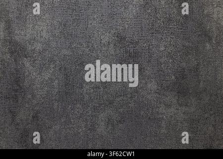 Dark grey textured wallcovering surface resembling aged concrete or slate. Abstract industrial background with mottled details and grunge aesthetic. Stock Photo