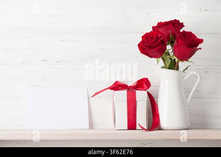Valentines day greeting card with rose flowers and gift box on white wooden background. With space for your greetings Stock Photo