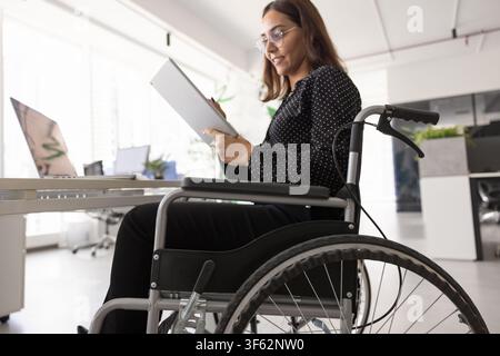 Professional woman with disability working on tablet sitting in wheelchair Stock Photo