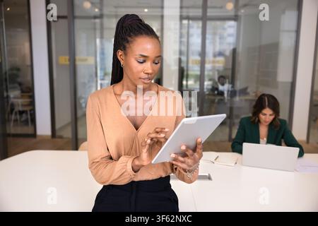 Attractive African female manager using digital tablet in office Stock Photo