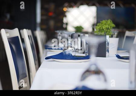 Table set for dinner at a restaurant with blue napkins Stock Photo