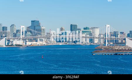 Rainbow Bridge a suspension bridge over Tokyo Bay and city skyline with blue sky and winter morning light in Tokyo Japan Stock Photo