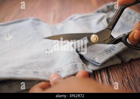 Cutting fabric with scissors on a wooden table Stock Photo
