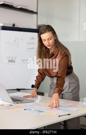 Businesswoman reviewing printed charts and documents, analyzing data in office Stock Photo