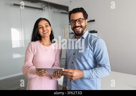 Smiling business colleagues, staff members holding tablet, looking at camera Stock Photo