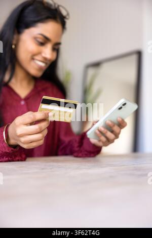 Woman uses smartphone and credit card to make online purchase Stock Photo