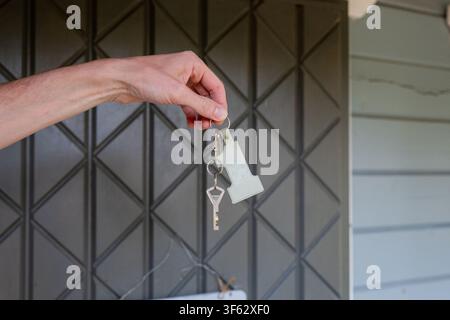 Hand holding house keys in front of residential mailbox after property access or home rental check in Stock Photo