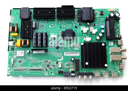 A topdown view of a complex green printed circuit board populated with various electronic components against a white background Stock Photo