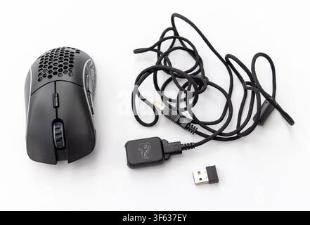 A black honeycomb gaming mouse is displayed alongside its braided cable and USB receiver on a white background Stock Photo