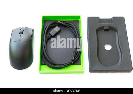 A black computer mouse is displayed alongside its packaging box and a braided USB cable on a white background Stock Photo