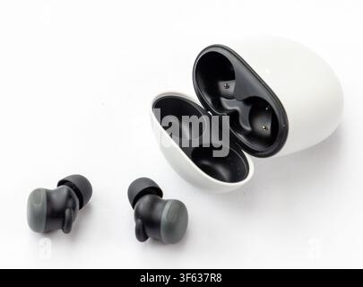A pair of wireless earbuds and their open charging case are displayed on a clean white background Stock Photo