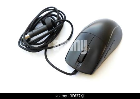 A black wired computer mouse with a neatly coiled braided cable rests on a clean white surface Stock Photo
