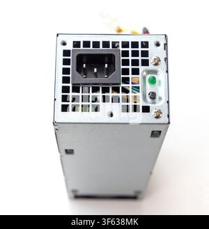 A computer power supply unit stands vertically isolated against a plain white background Stock Photo