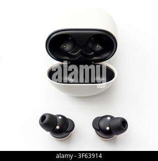A pair of black wireless earbuds and their open charging case are displayed on a clean white background Stock Photo