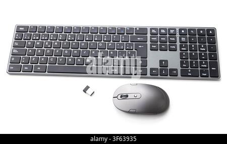 A wireless computer keyboard and mouse with its USB receiver are displayed on a white background Stock Photo