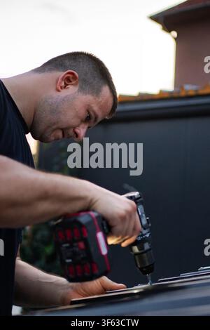 Man using power drill for construction work outdoors Stock Photo