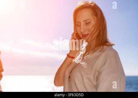 Woman smartphone beach middle aged female talks on a cell phone while standing by the ocean on a sunny day Stock Photo