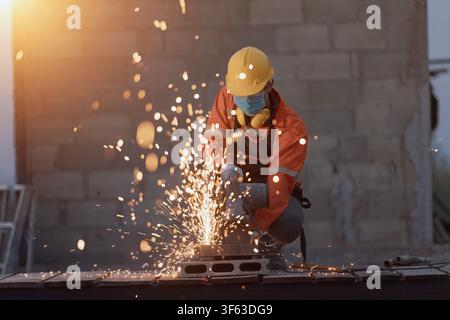Close-up of a Welder in protective workwear using an angle grinder on a construction site, Thailand Stock Photo