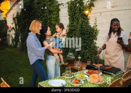 Multi ethnic friends enjoying backyard barbecue party with baby Stock Photo