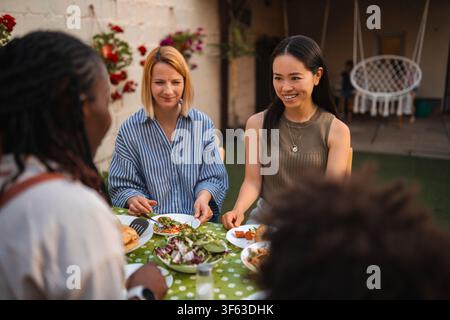 Multi ethnic women friends enjoying outdoor dinner party Stock Photo