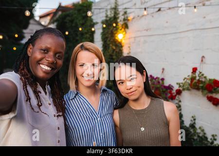 Happy diverse women friends taking selfie at backyard party Stock Photo