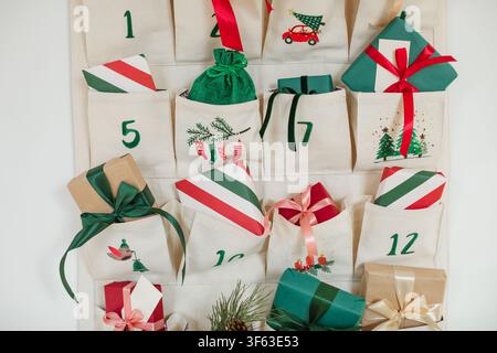 Close-up of part of a Traditional Christmas advent calendar with assorted wrapped gifts hanging on a white wall Stock Photo