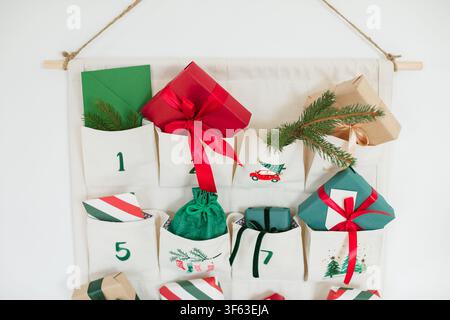 Close-up of part of a Traditional Christmas advent calendar with assorted wrapped gifts hanging on a white wall Stock Photo