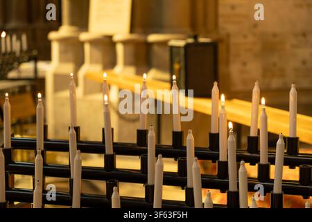 Rows of white prayer candles burning inside historic church Stock Photo