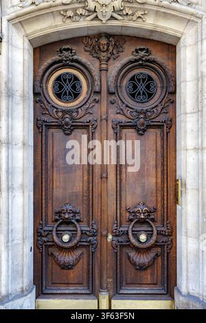Ornate Carved Wooden Double Door with Circular Iron Grilles and Stone Frame Stock Photo