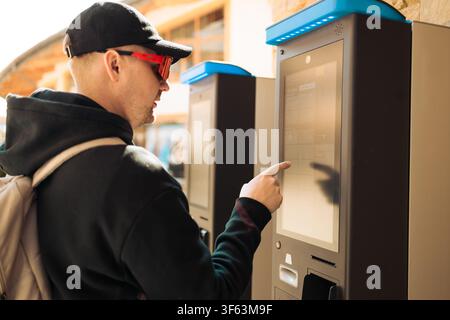 Young man using outdoor automated ticket machine or parking meter Stock Photo