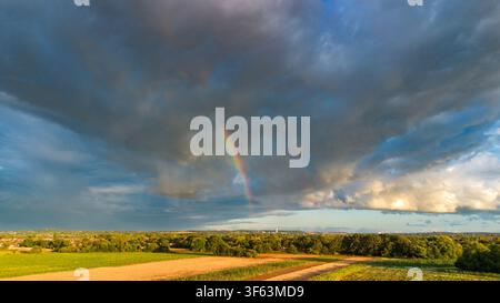 Brooding dark clouds and rainbow over fields in Cheshire. Stock Photo