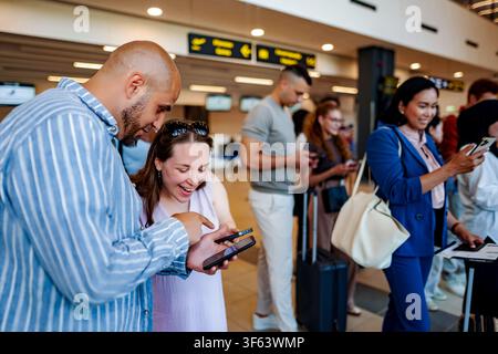 People using smartphones waiting in airport queue Stock Photo