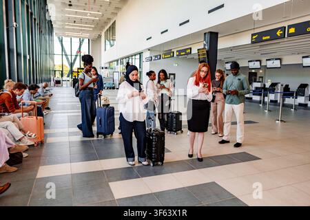Diverse people traveling, waiting in airport terminal, using smartphones Stock Photo