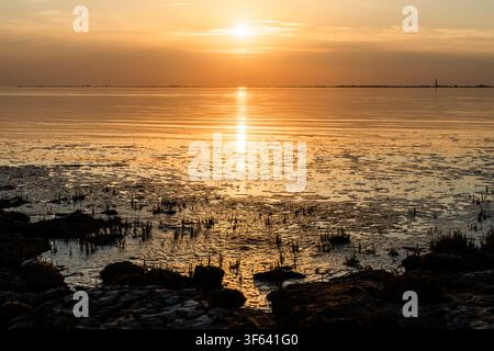 Sunset over the Wadden Sea on the North Sea coast at Hilgenriedersiel Natural Beach. Aurich District, Lower Saxony, Germany. Stock Photo