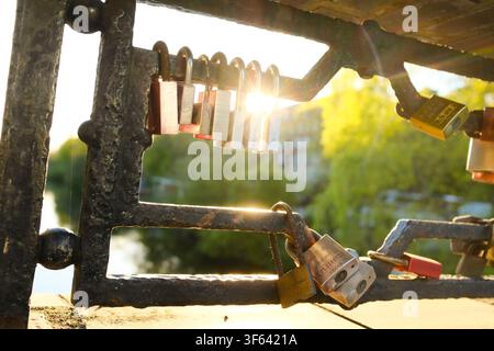 Love locks on the bridge over the Goldbek Canal in Hamburg. The rising morning sun makes the locks glow against the light. Stock Photo