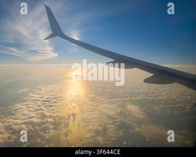 Airplane wing above the clouds at sunrise over the Adriatic Sea during a flight Stock Photo