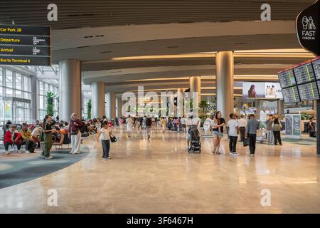 Singapore - December 25,2025 : Travelers walk and wait inside the spacious departure hall of Changi Airport Terminal 2 in Singapore. Stock Photo